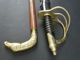 a gold and black sword with a wooden handle on a black surface