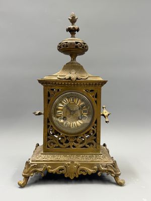 a gold clock with a bird on top of it