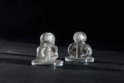 two glass figurines of people sitting on top of a table