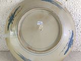 a blue and white plate on a table with a white wall behind it