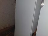 two white refrigerators in a room with a brick wall