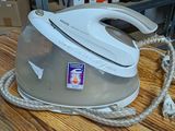 a white steam iron on a wooden table in a room