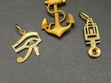 trois breloques en or représentant un œil égyptien, un œil d'Horus et un œil d'Horus