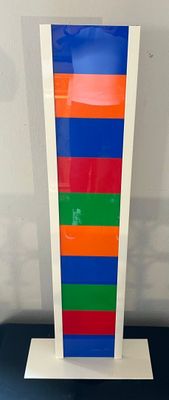a multicolored vase on a white stand on a table