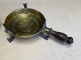 an old brass plate with a wooden handle on a table