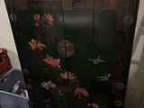 a black cabinet with flowers painted on it and a basket on the floor
