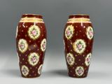 une paire de vases rouges ornés de fleurs dorées et roses