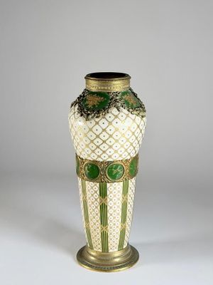 un vase vert et blanc posé sur une surface blanche