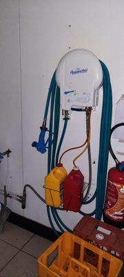 une photo d'une salle de bains avec des toilettes et un tuyau accroché au mur