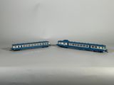 deux wagons bleus et blancs placés côte à côte sur une surface blanche