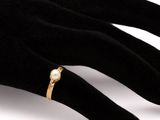 an image of a woman ' s hand wearing a gold ring with a pearl on it
