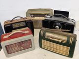 Plusieurs radios à l'ancienne sont alignées sur une table