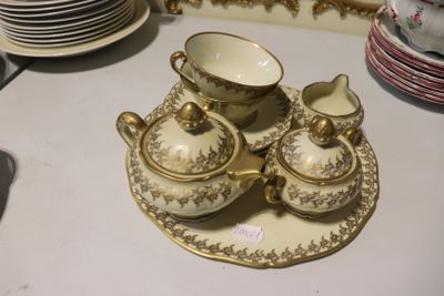 une table blanche sur laquelle sont disposées des assiettes, des tasses et des soucoupes