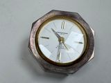 une horloge argentée et dorée posée sur un fond blanc