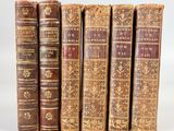 cinq vieux livres sont alignés sur une surface blanche