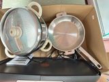 deux casseroles et poêles dans une boîte posée sur une table