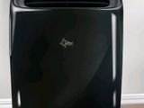 a black air conditioner sitting on the floor in front of a window