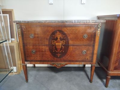 a chest of drawers that has a coat of arms on it