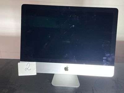 un écran d'ordinateur posé sur un bureau, avec une note accrochée dessus
