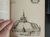 a person holding a book with a drawing of a castle on it