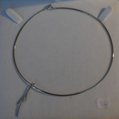 un collier en argent muni d'un crochet, posé sur une surface blanche