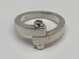 une bague en argent ornée d'une croix, posée sur un fond blanc
