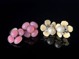 deux paires de fleurs roses et blanches et des perles sur un fond noir