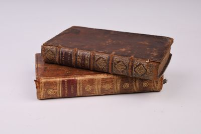 deux vieux livres posés l'un sur l'autre sur une surface blanche