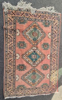 un vieux tapis orné d'un motif en losanges, posé à même le sol