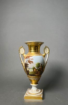 a gold vase with a painting on it sitting on a table