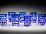 six verres en verre bleu sont alignés sur une surface blanche