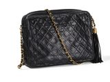 a black quilted bag with a chain strap and tassel