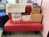 un banc rouge sur lequel sont posées des boîtes, dans une pièce