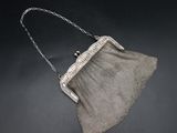 an old silver mesh purse with a chain handle on a black surface