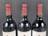 three bottles of red wine sitting on a table next to each other