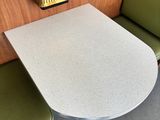 a small table and two green chairs in a booth