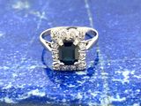 une photo d'une bague sertie d'un saphir bleu et de diamants, posée sur une pierre bleue