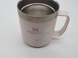 une tasse rose avec une anse, posée sur une table blanche