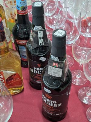 many bottles of alcohol sitting on a table with wine glasses
