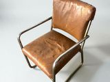 brown leather chair with metal frame and armrests against a white backdrop