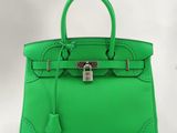 un sac à main en cuir vert muni d'un cadenas sur la poignée
