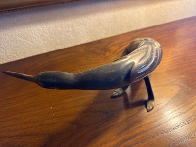 sculpture représentant un oiseau posée sur une table en bois, avec un miroir en arrière-plan