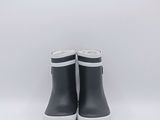 une paire de bottes de pluie noires posées sur une surface blanche