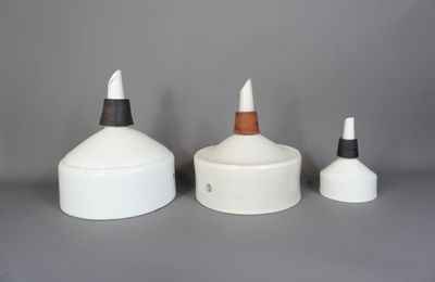 trois vases blancs et noirs posés les uns à côté des autres sur une surface grise