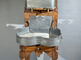 une chaise en bois sur laquelle est posé un plateau en métal