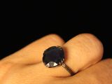 a person ' s hand holding a ring with a blue stone
