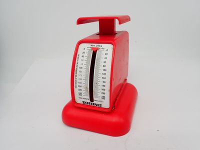 une image représentant une balance rouge posée sur une table blanche