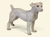 une petite statue représentant un chien debout sur une surface blanche