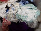 a basket full of clothes that is sitting on a bed