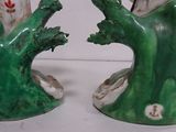 two green vases with flowers on them on a table